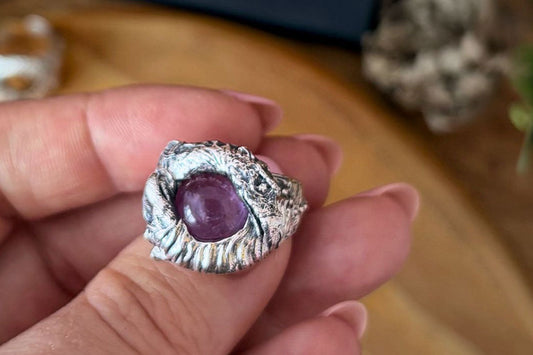 Close-up of the Skeksis & Mystic Ring on hand, showing the amethyst stone and sculpted silver details inspired by The Dark Crystal™.