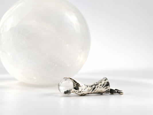 Labyrinth Goblin King hand holding crystal ball necklaces in silver and gold finishes, styled on a dark magical setting.