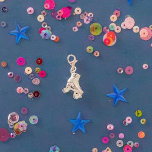 Starlight Express roller skate charm on a vibrant blue background decorated with sequins and stars, styled in a playful theatre-inspired flat lay.