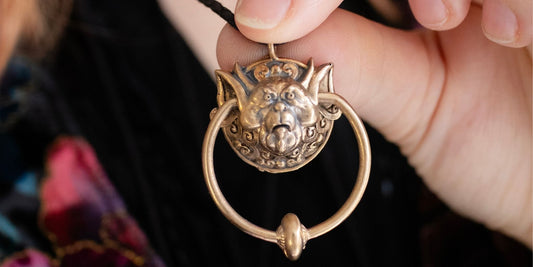 Licensed To Charm Labyrinth bronze Ludo necklaces displayed in hand