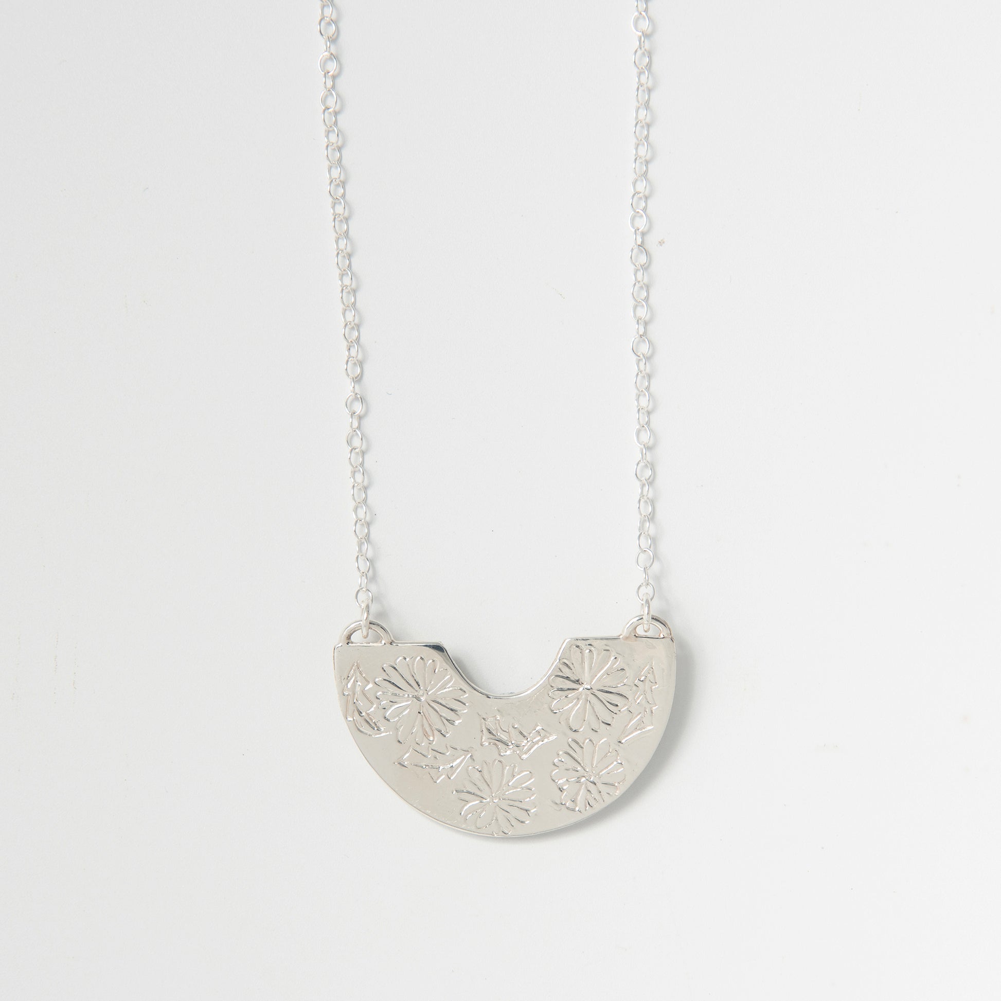 Sterling silver Frida Kahlo Creole Necklace featuring engraved marigold semi-circle pendant on a delicate chain.