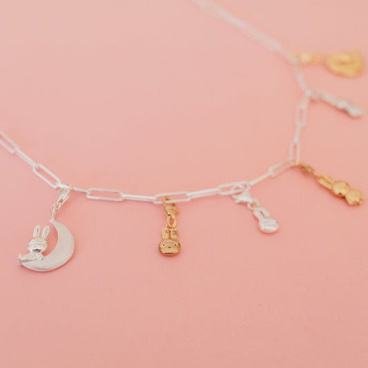 Sterling silver Miffy large head charm attached to a sterling silver paperclip bracelet, styled on a soft pink background.