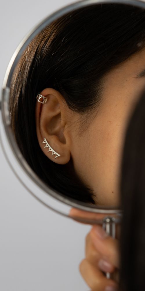 Licensed To Charm National Portrait Gallery sterling silver ear climber and stud earrings styled on model, close up mirror shot