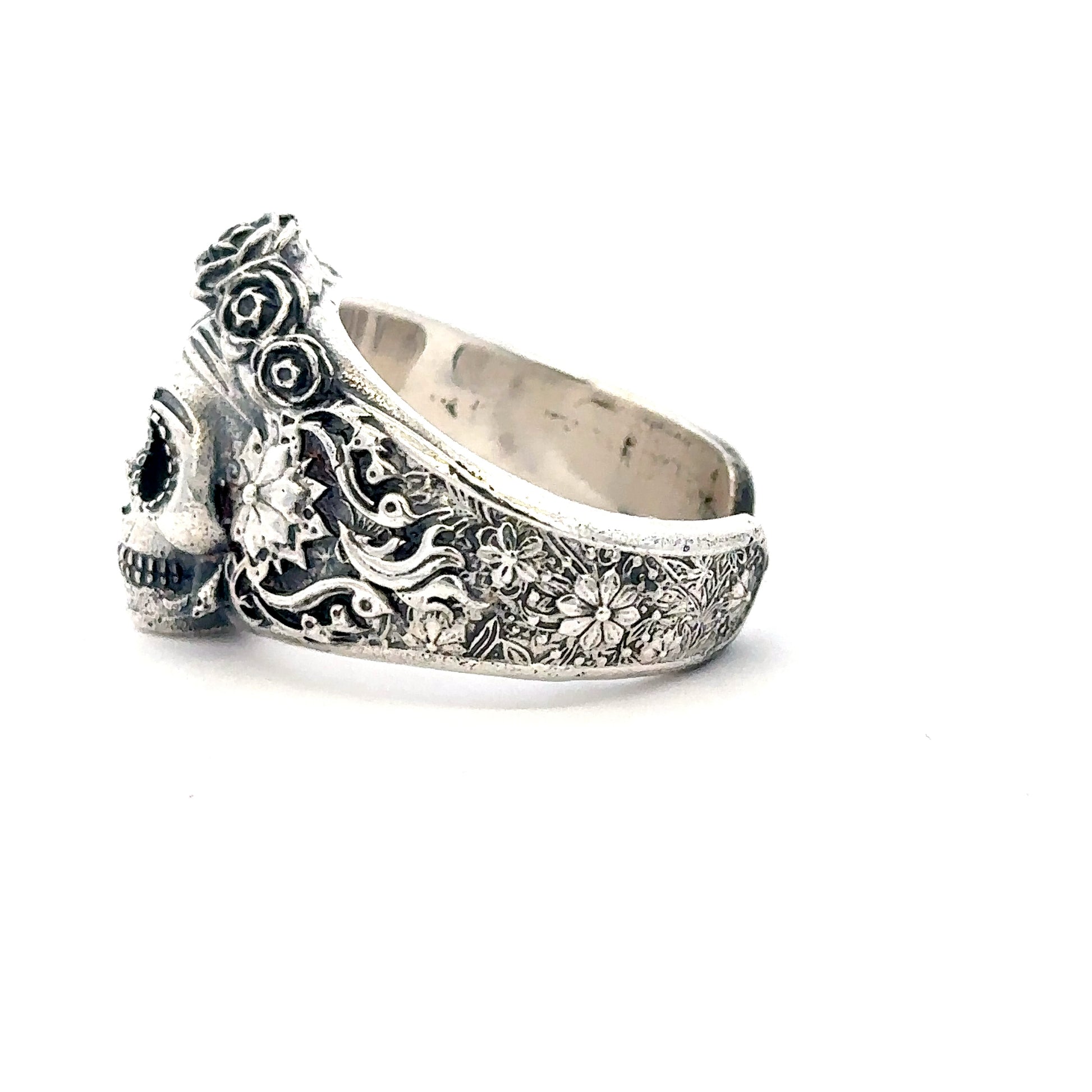 Silver skull and floral design ring on a white background