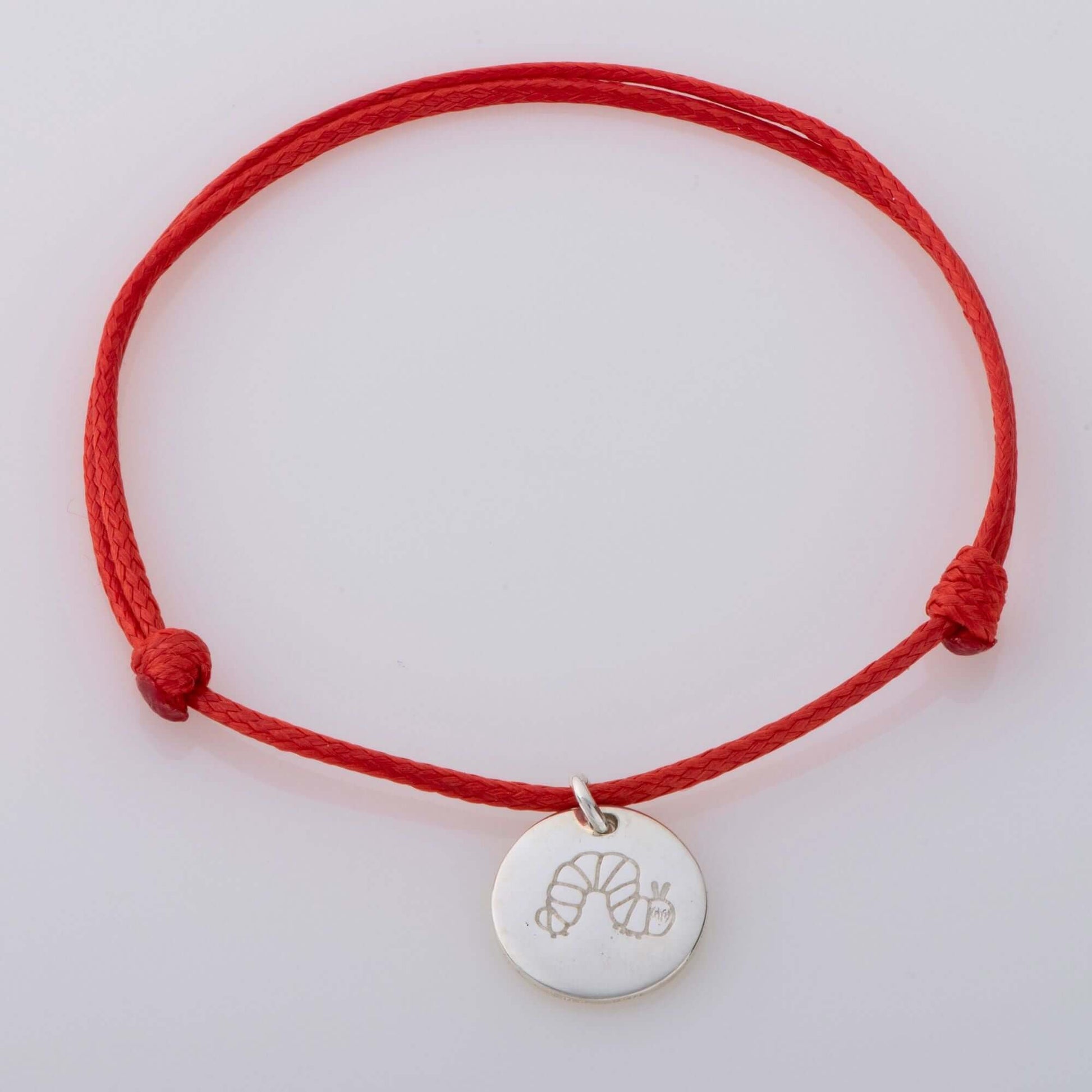 A sterling silver disc bracelet featuring The Very Hungry Caterpillar, suspended on a red cord. A playful, nostalgic accessory for book lovers of all ages.