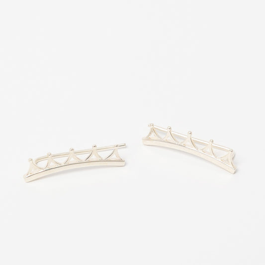 Close-up of handcrafted silver ear climbers with tiara-inspired curves, designed to follow the ear’s contour.