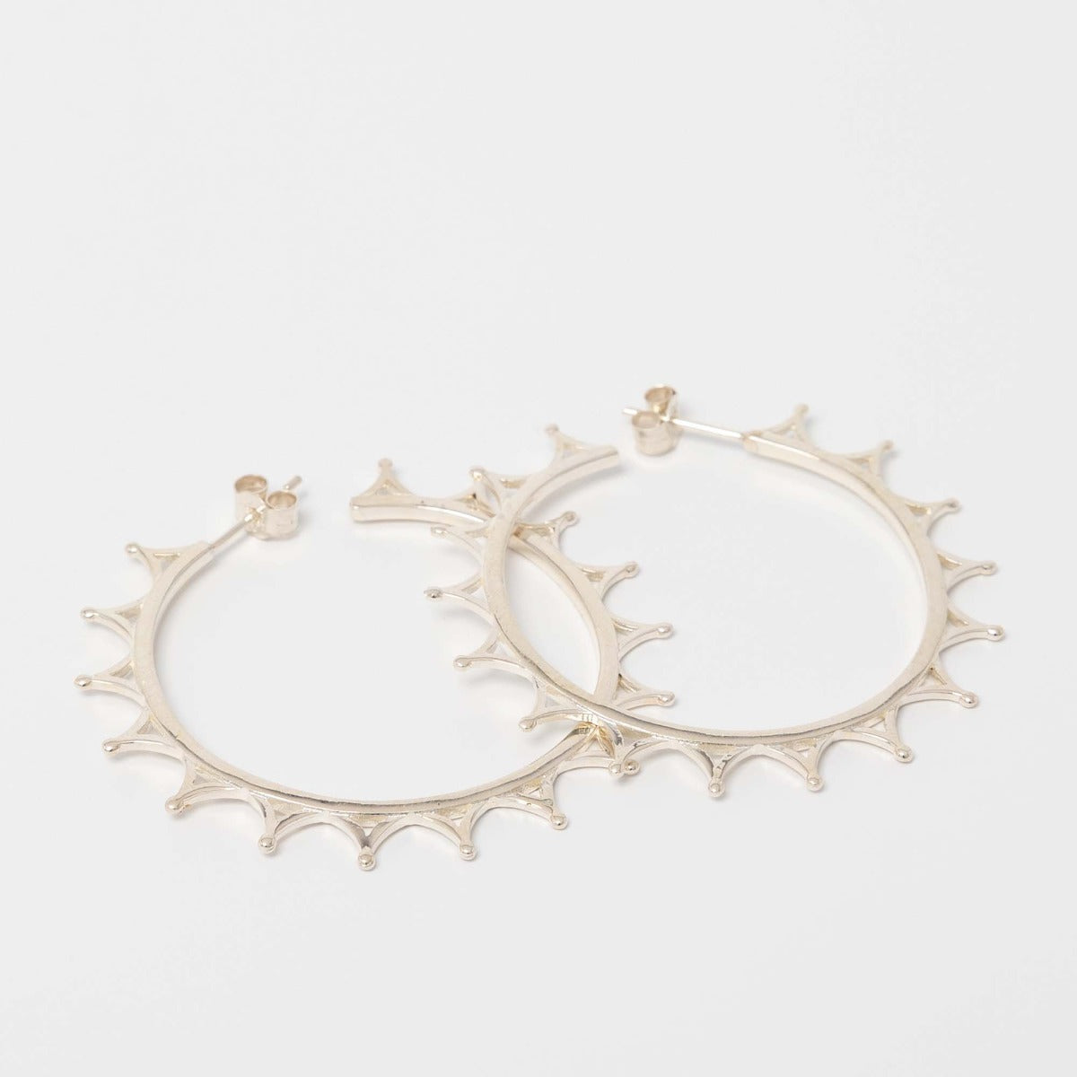 Sterling silver crown hoop earrings, inspired by Queen Elizabeth II’s tiara, handcrafted from recycled silver. Elegant and timeless, part of the Jubilee Crown Collection.