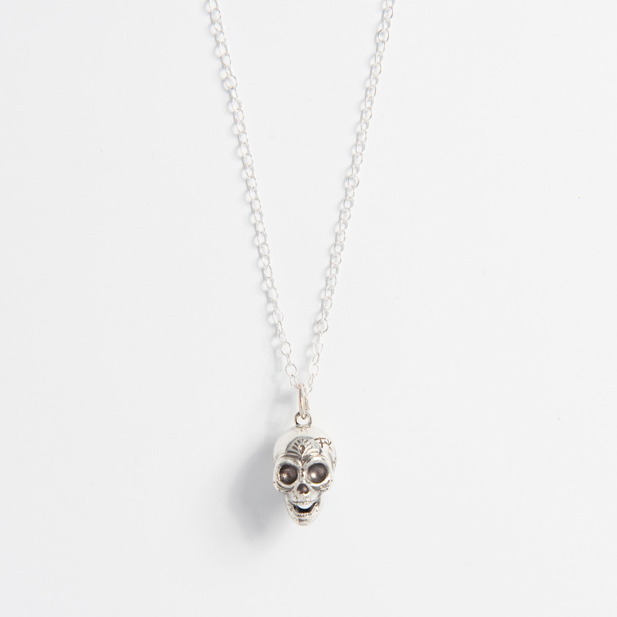 Front-facing view of the Frida Kahlo Calavera Skull Necklace in recycled sterling silver, featuring a detailed skull charm on a delicate trace chain.