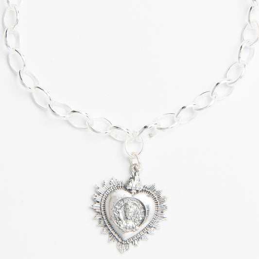 Close-up of heart-shaped charm featuring Frida Kahlo’s portrait surrounded by flowers and a bird.