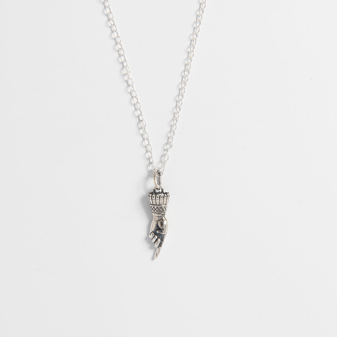 Front-facing view of the Frida Kahlo Pointing Hand Charm Necklace in sterling silver, showing the hand pendant with downward-pointing index finger.