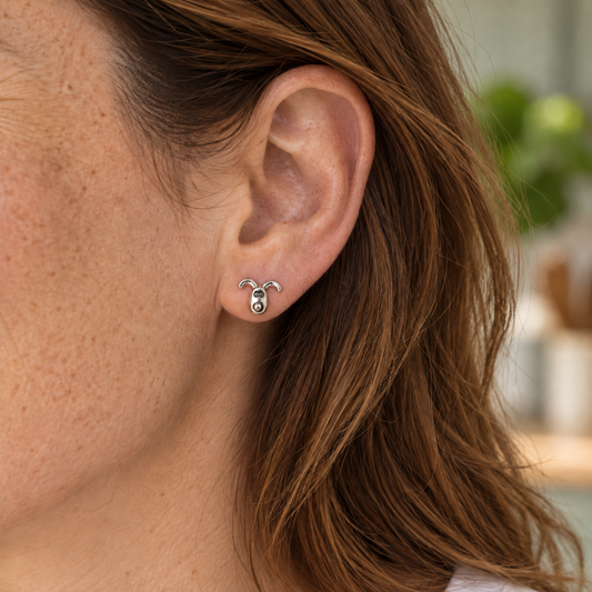 Close-up of a small sterling silver Gromit stud earring worn on an earlobe, showing the character’s face and curved ears.