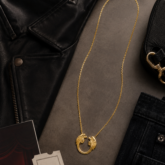 Gold plated Jesus Christ Superstar large pendant necklace styled in a flat lay with black leather, dark denim and theatre night accessories.
