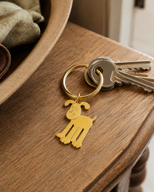 Licensed To Charm Gromit gold keyring attached to house keys on a wooden hallway table.