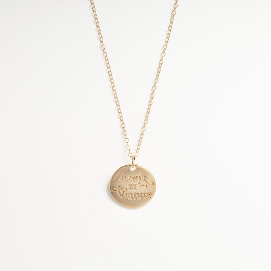 Close-up of the Amor et Virtute gold vermeil pendant, highlighting the engraved motto and reflective polished finish.
