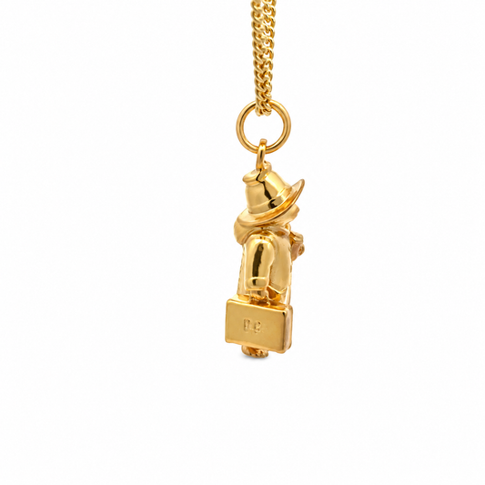 Full view of the Paddington Full Body Necklace in 18ct gold vermeil, showing the miniature character pendant hanging from a gold chain holding suitcase with PB