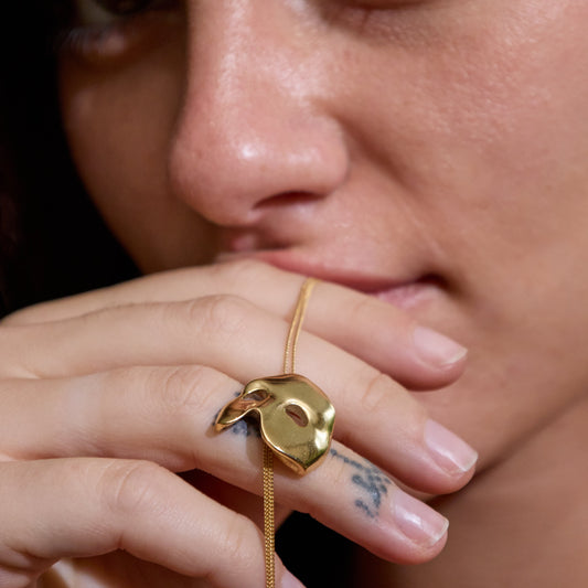 Close-up showing sculpted detailing of Andrew Lloyd Webber's Phantom of the Opera gold mask pendant