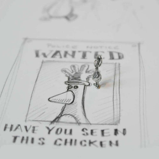 Feathers McGraw sterling silver charm displayed on a Wallace & Gromit-style wanted poster – quirky handmade jewellery inspired by the iconic character.