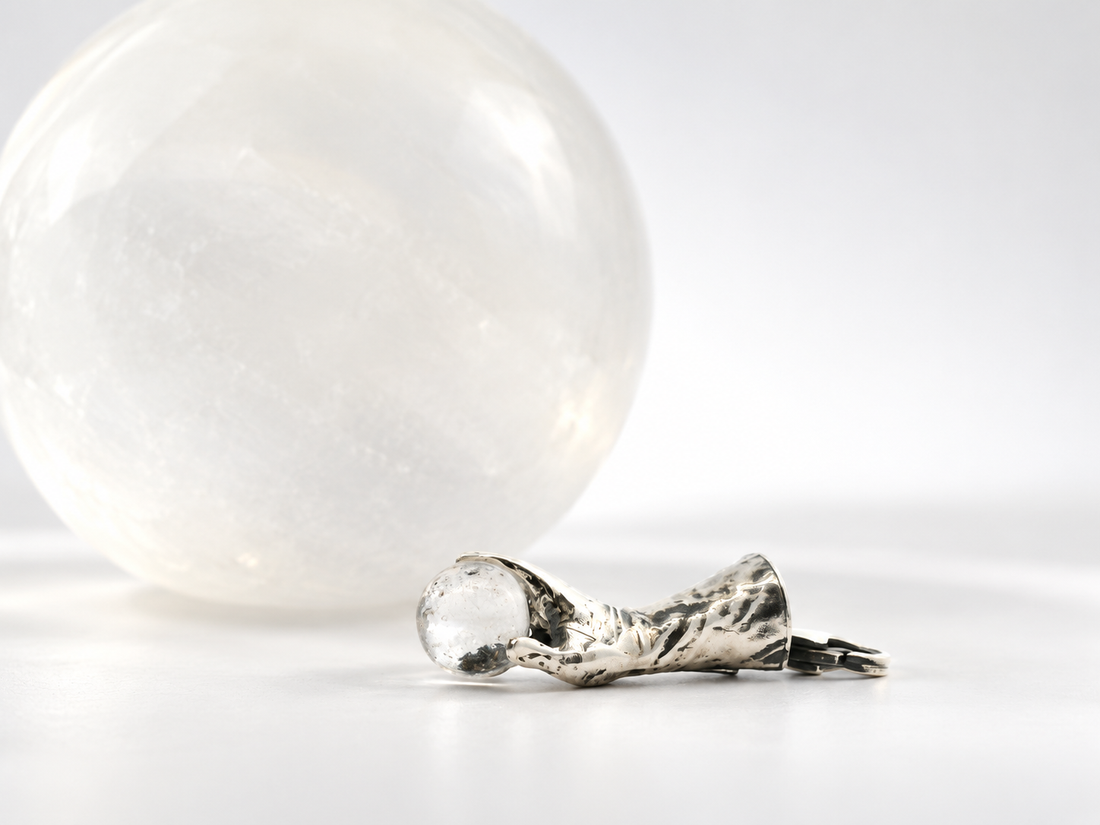 Labyrinth Goblin King hand holding crystal ball necklaces in silver and gold finishes, styled on a dark magical setting.