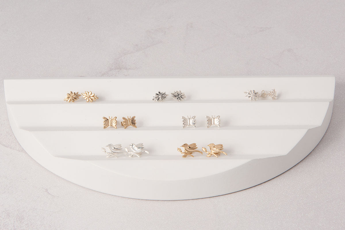 Licensed To Charm Frida Kahlo sterling silver and gold stud earrings displayed on white jewellery stand, butterfly and floral designs