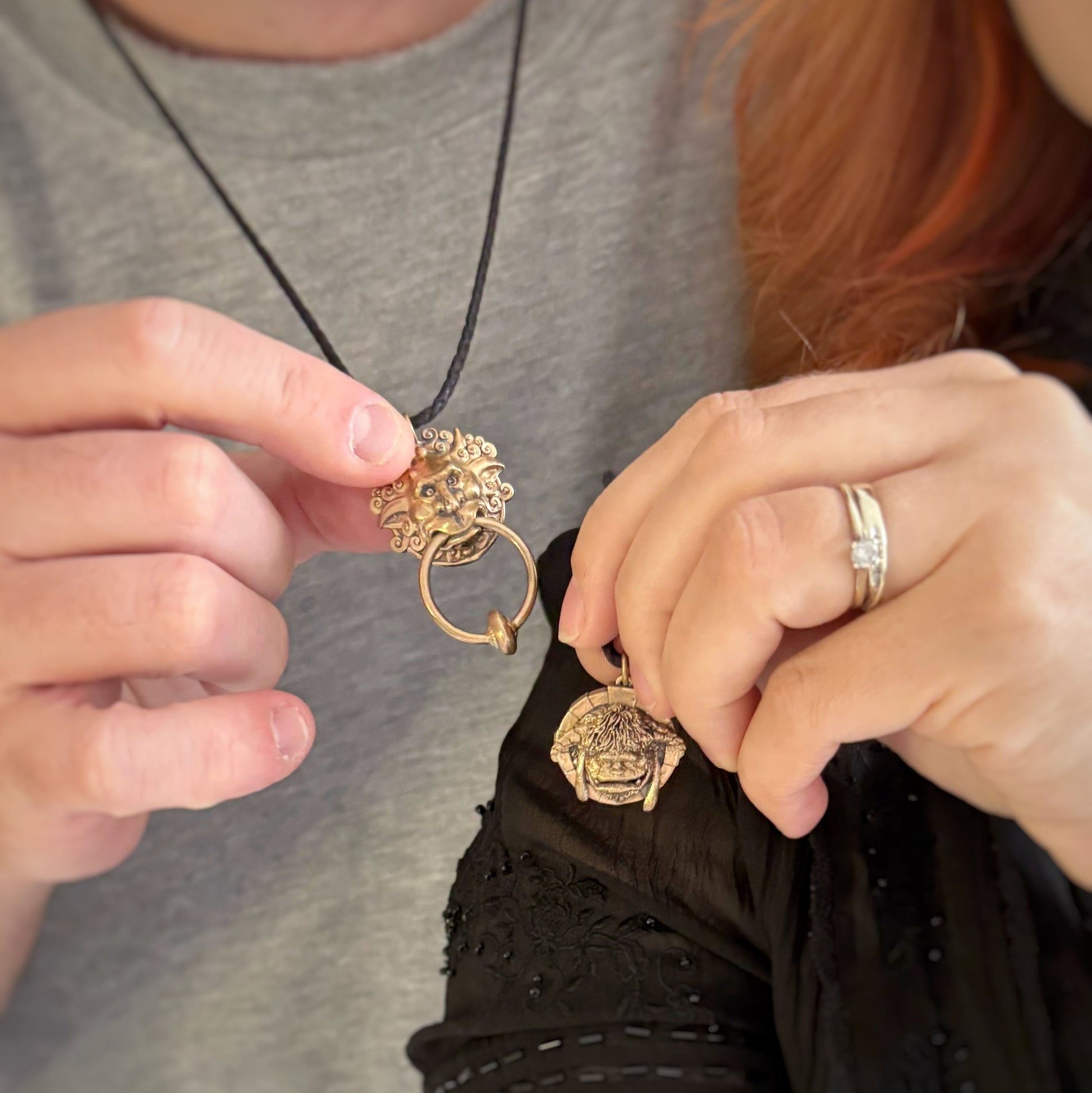 Licensed To Charm model holding the Labyrinth Left Door Knocker and Ludo bronze necklace on an adjustable black cord