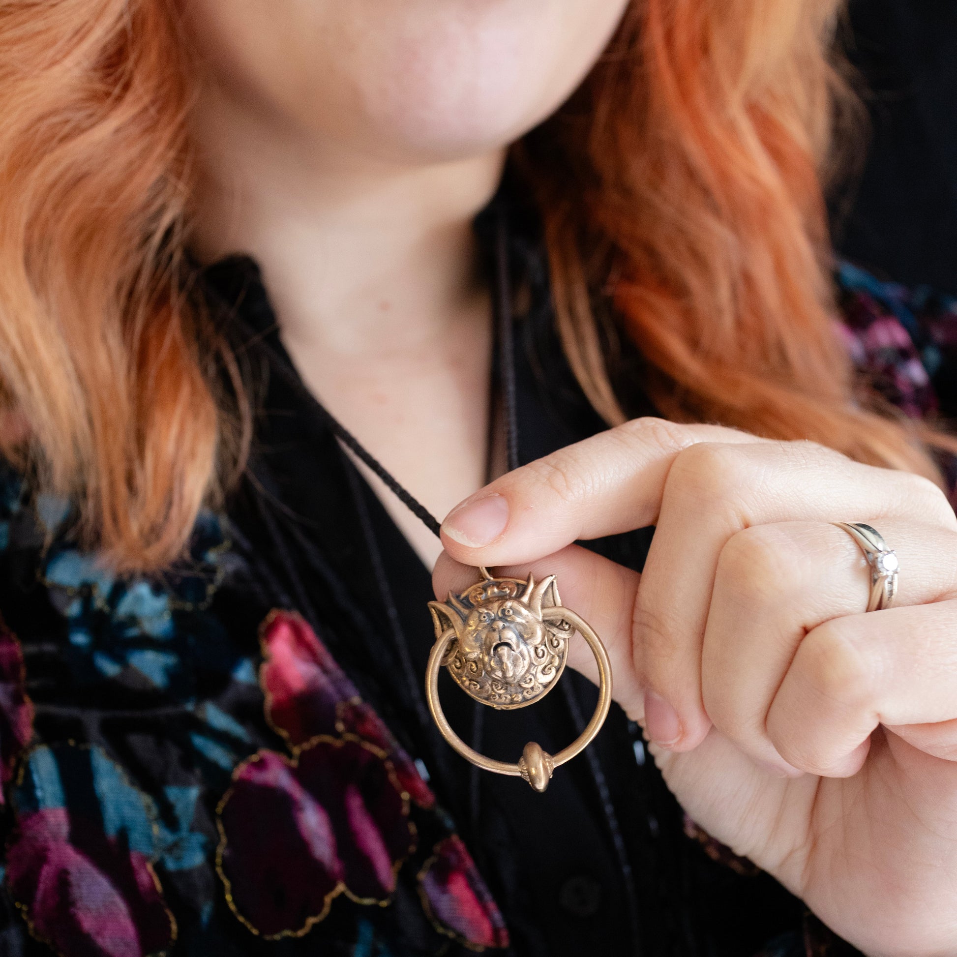 Licensed To Charm model holding the Labyrinth Right Door Knocker bronze necklace on an adjustable black cord