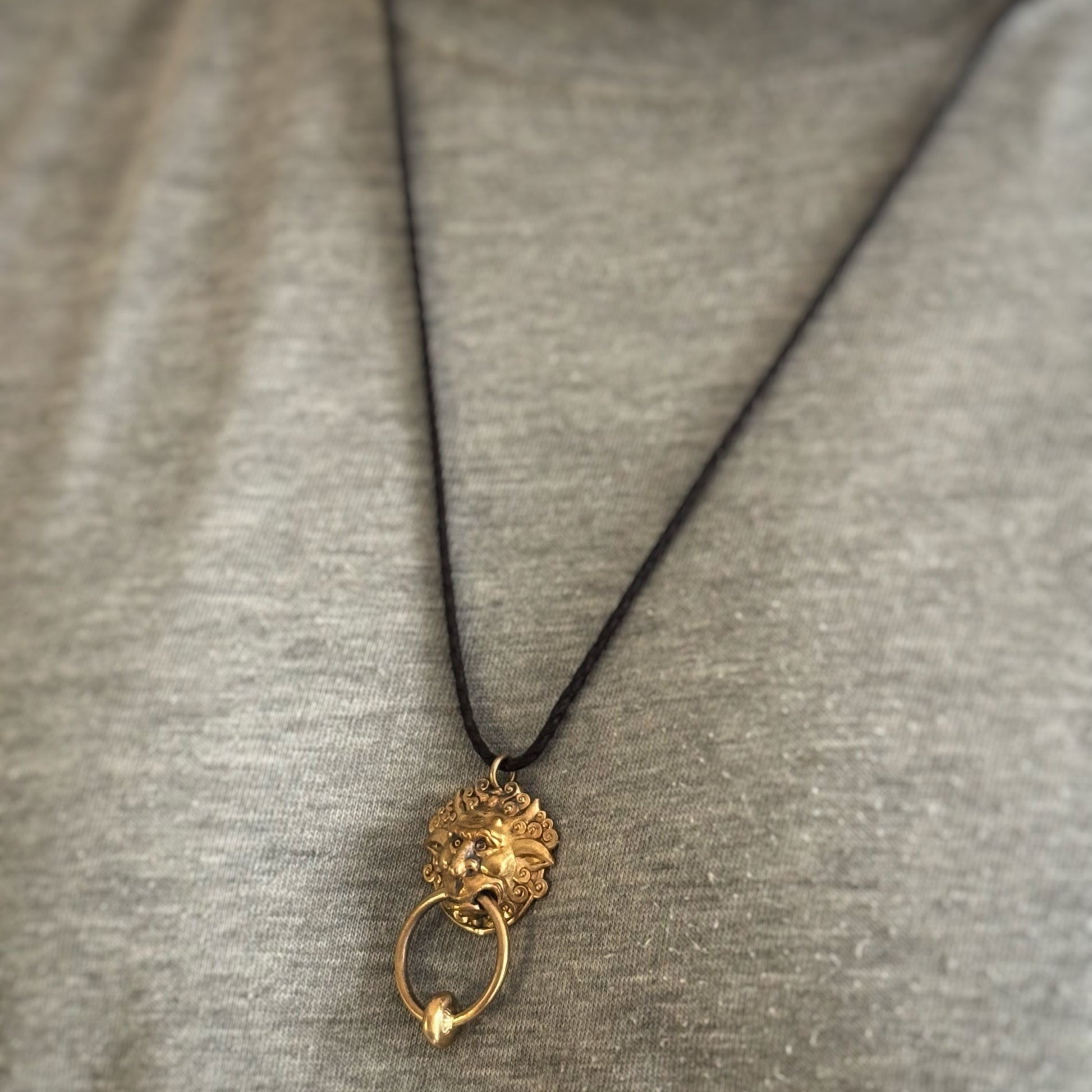 Licensed To Charm Labyrinth Right Door Knocker bronze necklace worn on an adjustable black cord against a grey top