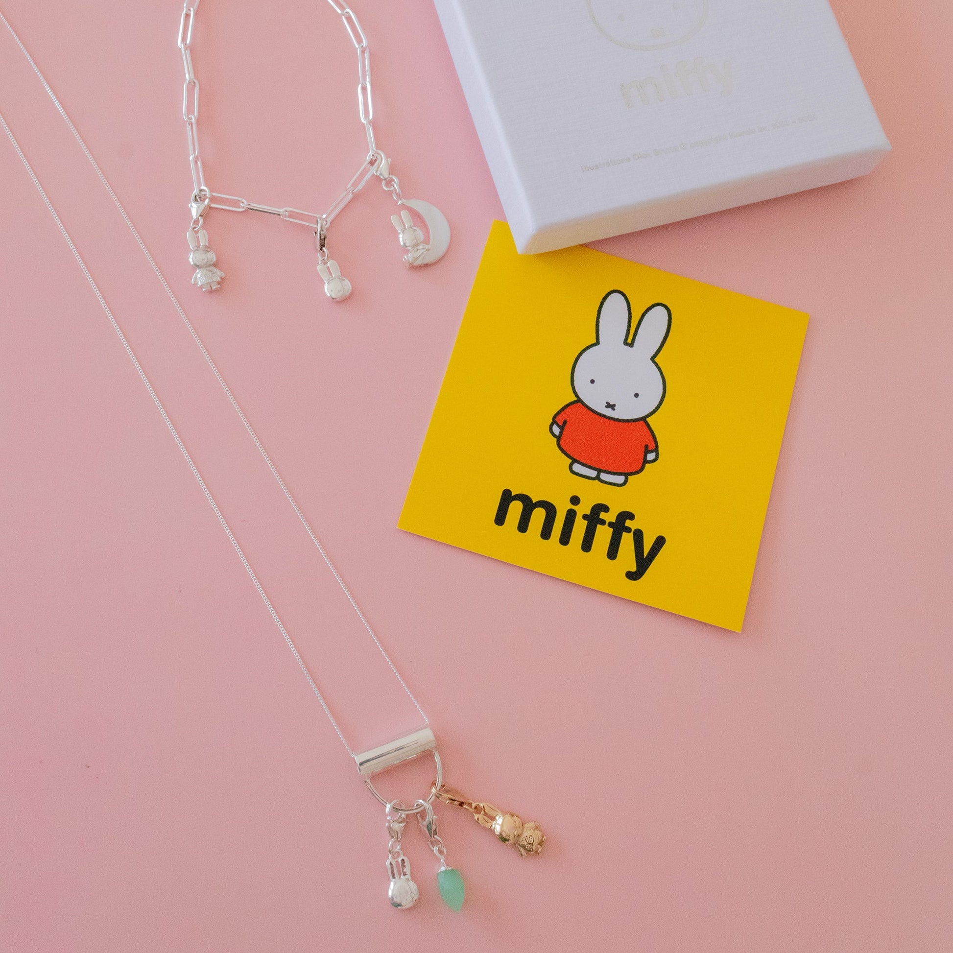 Sterling silver Miffy charms styled on a bracelet and necklace, shown with branded Miffy gift box on a pink background.