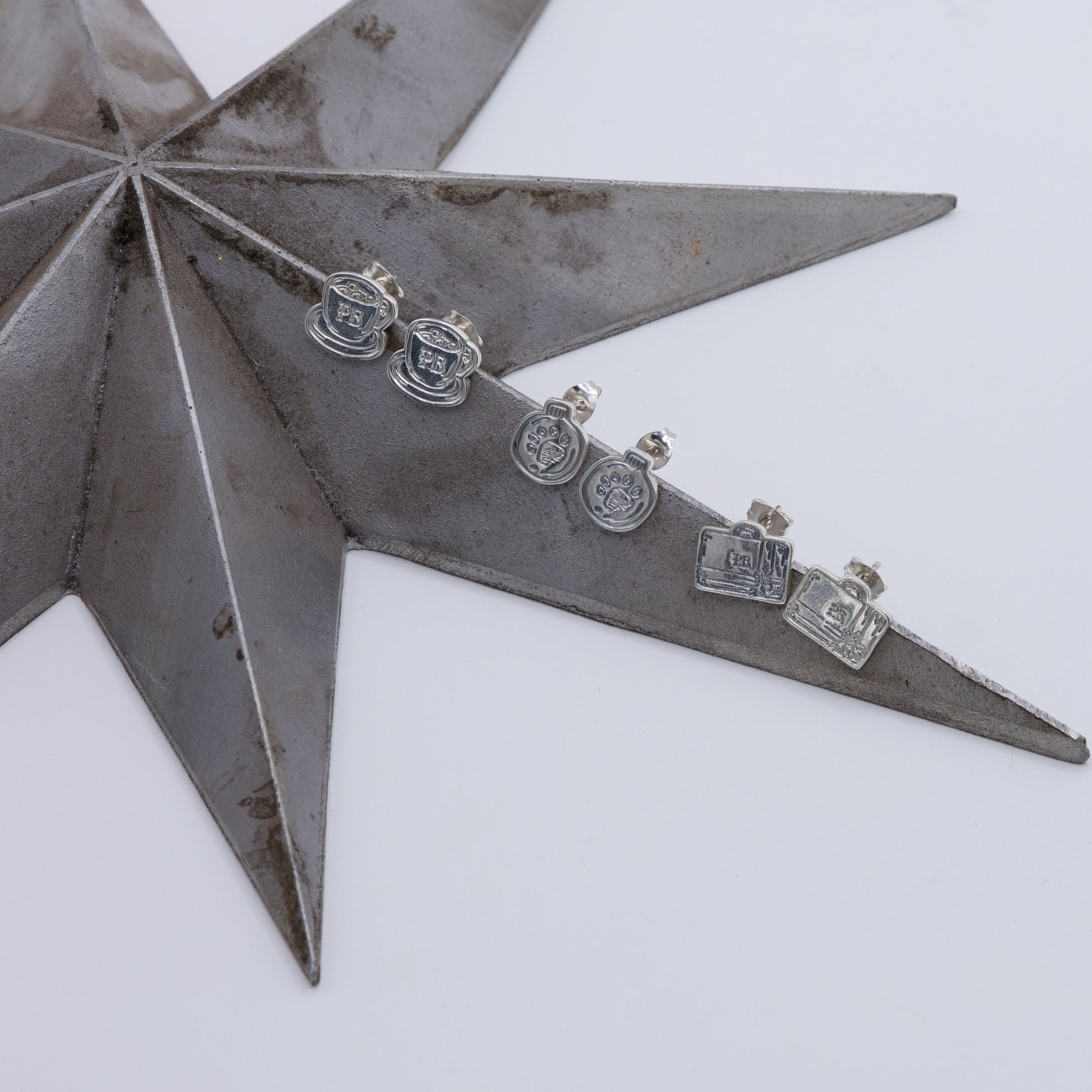 Metallic star-shaped displaying Licensed To Charm Paddington bauble pawprint earrings  for Christmas gifting