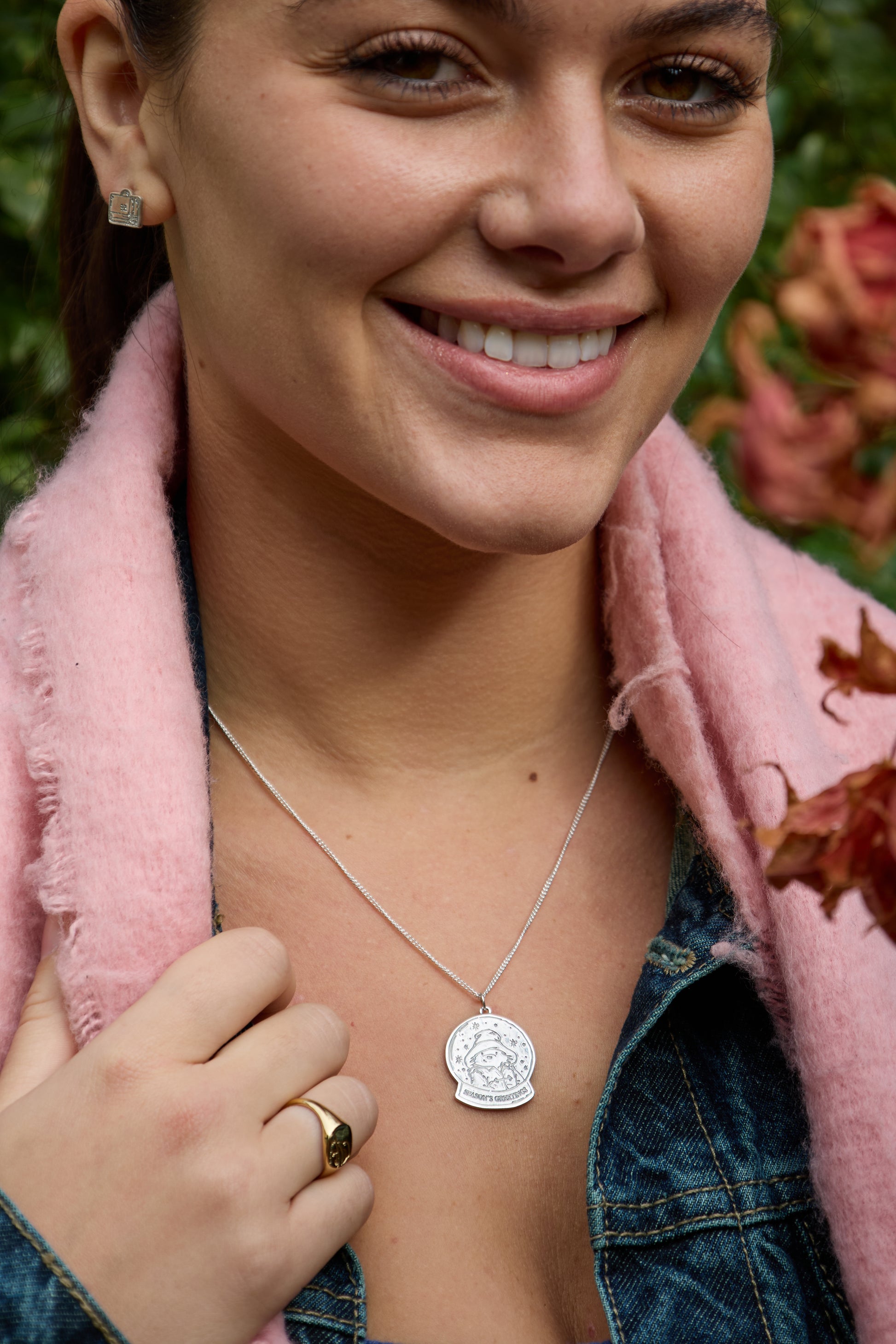 Paddington luggage stud earrings with bow displayed with Christmas décor worn by model, sterling silver – Licensed To Charm