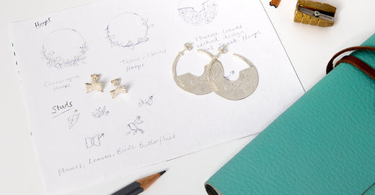 Sketches and handmade silver hoop earrings in the Licensed To Charm studio, showing the jewellery design process inspired by Frida Kahlo’s artistry.