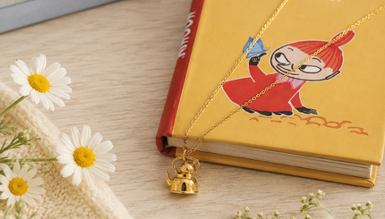 Licensed To Charm officially licensed Moomin jewellery Little My gold vermeil necklace styled with a Moomin book in a nostalgic lifestyle setting.