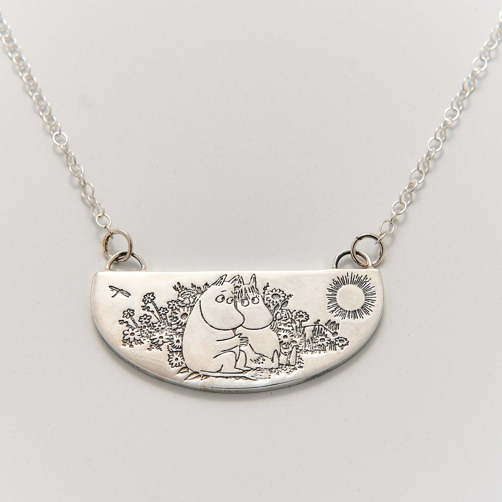 Moomin Friends Among Flowers Necklace in sterling silver, featuring a hand-engraved pendant of Moomintroll and Snorkmaiden in a meadow.