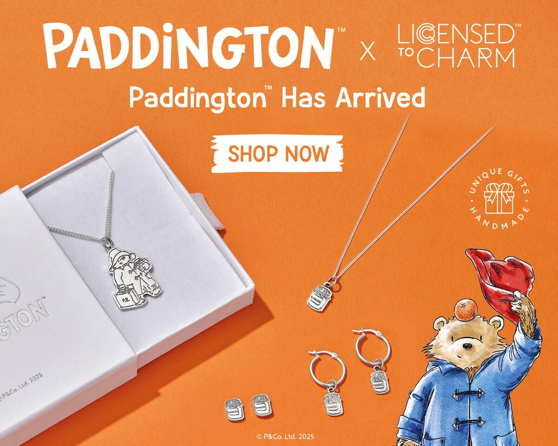 Licensed To Charm official Paddington™ jewellery launch banner featuring sterling silver necklace, marmalade jar hoop earrings and studs on orange background with Paddington illustration