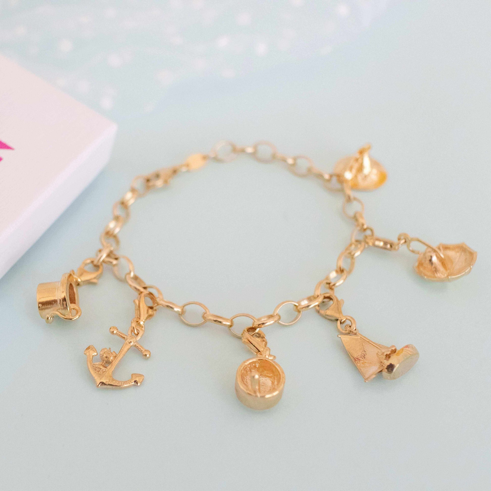 Gold vermeil Nibling in Umbrella charm displayed flat on a plain surface, capturing the elegant lines and rich finish.
