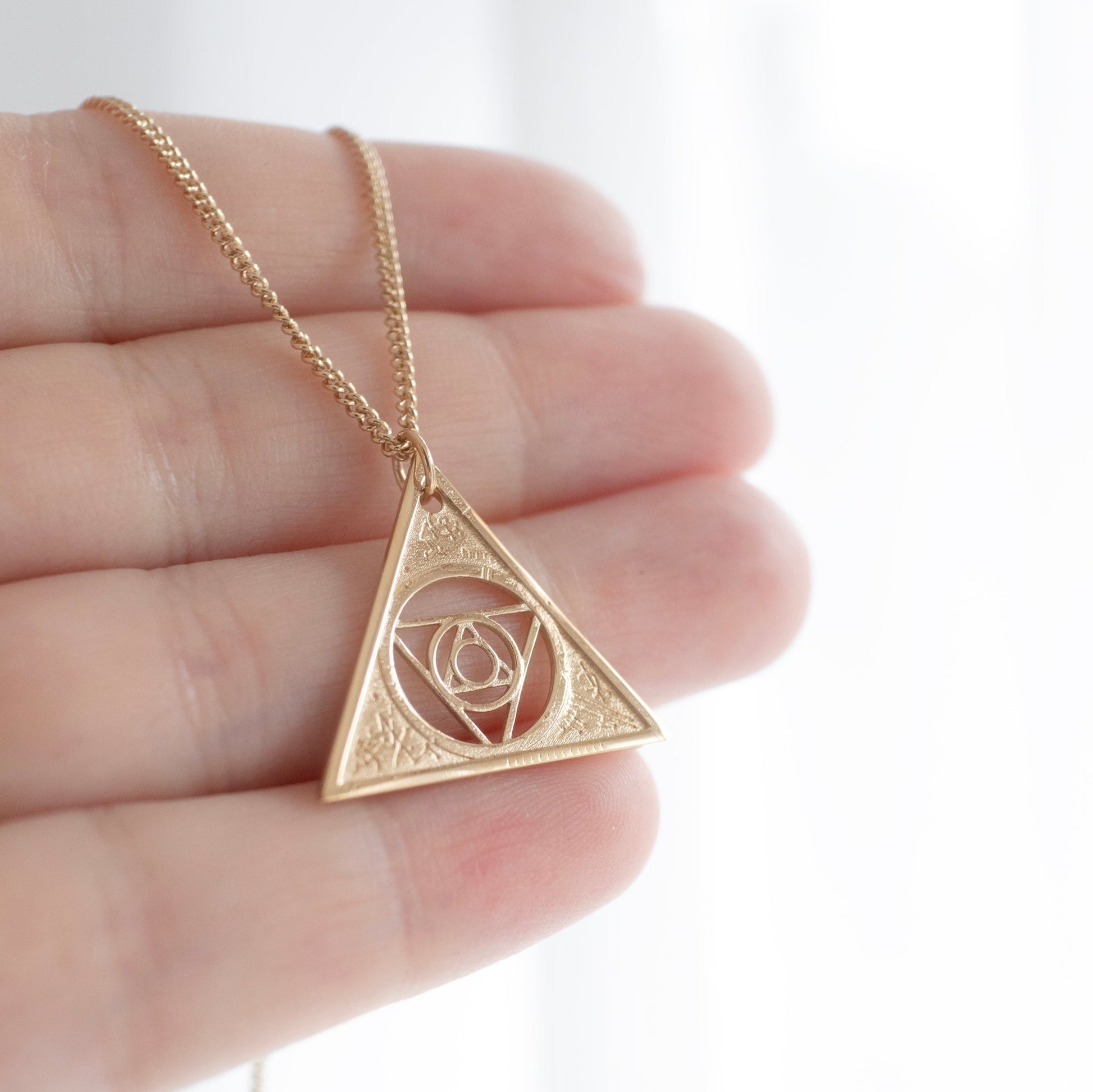 Gold Vermeil Aughra's Triangle Necklace with a 45 cm trace chain, showcasing the Eye of the superimposed suns and cosmic triangle design. A tribute to the lore of The Dark Crystal