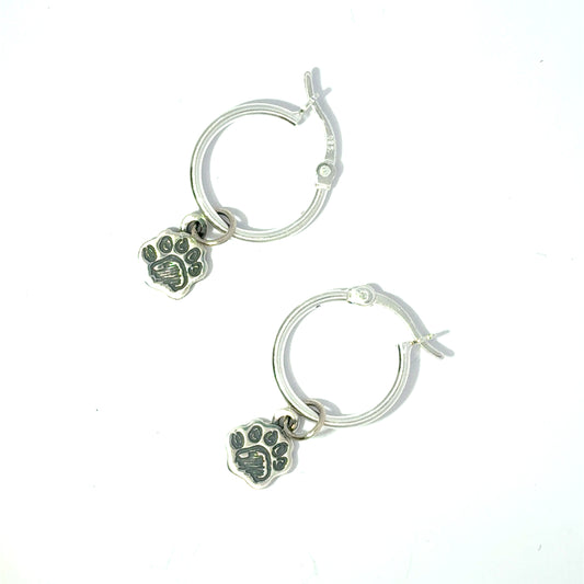 Sterling silver hoop earrings with dangling Paddington Bear paw print charms on a white background