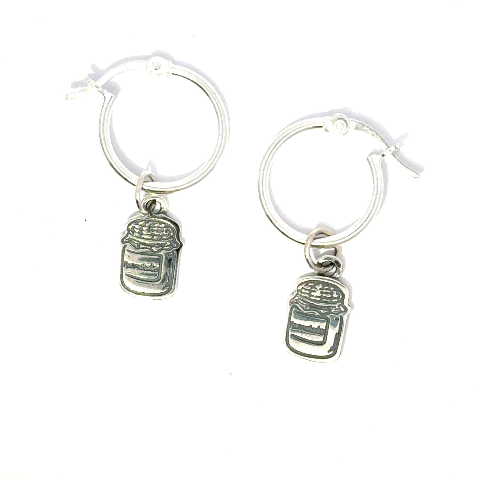 Close-up side view of silver hoop earrings showing Paddington-inspired marmalade jar and toast charms