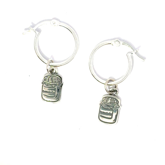 Close-up side view of silver hoop earrings showing Paddington-inspired marmalade jar and toast charms
