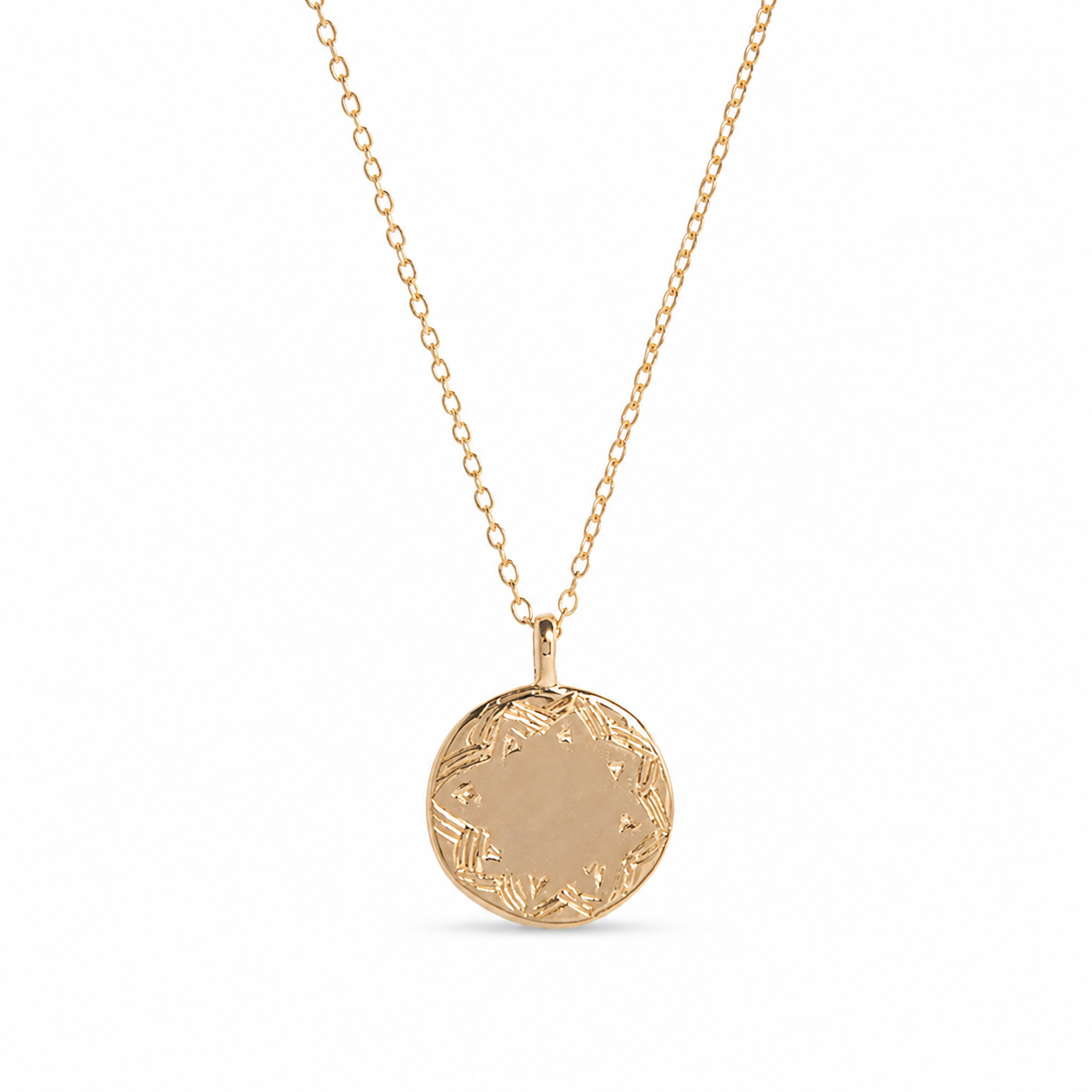 A Frida kahlo gold pendant necklace featuring a round, flat gold disc pendant with a delicate floral border engraving, suspended from a fine gold chain against a solid white background.