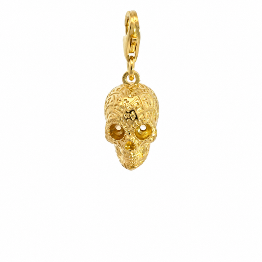 Front view of the Frida Kahlo gold skull charm, showing intricate engraved patterns and a lobster clasp against white.