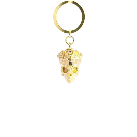 A brass metal keychain featuring a Frida Kahlo as sugar skull pendant adorned with a crown and a small rhinestone, attached to a split key ring against a plain white background.