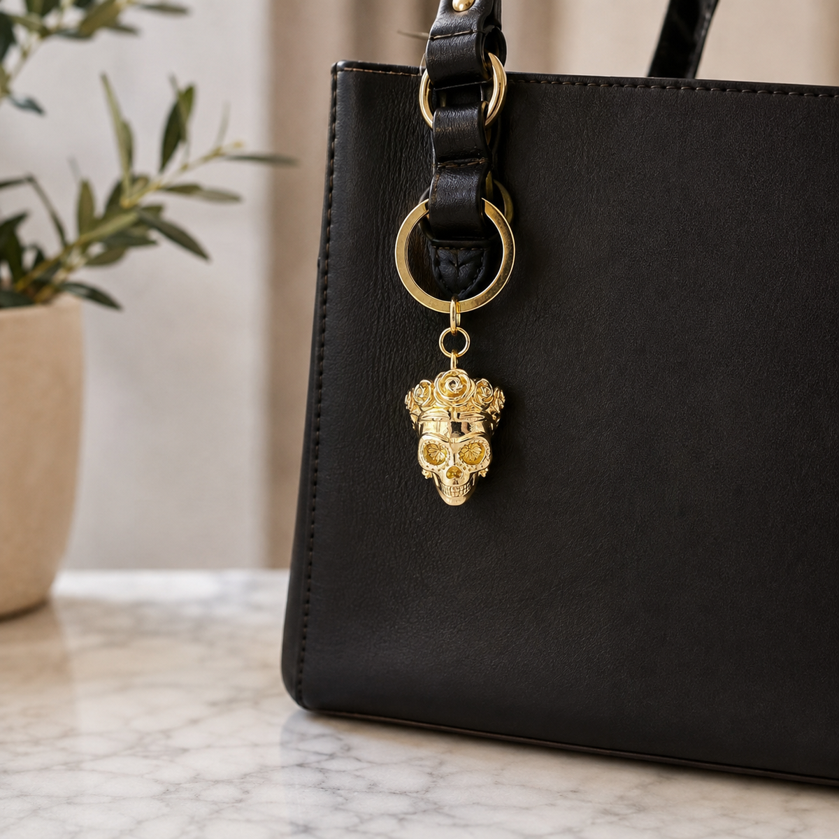 Frida Kahlo skull brass keyring used as a bag charm on a black handbag
