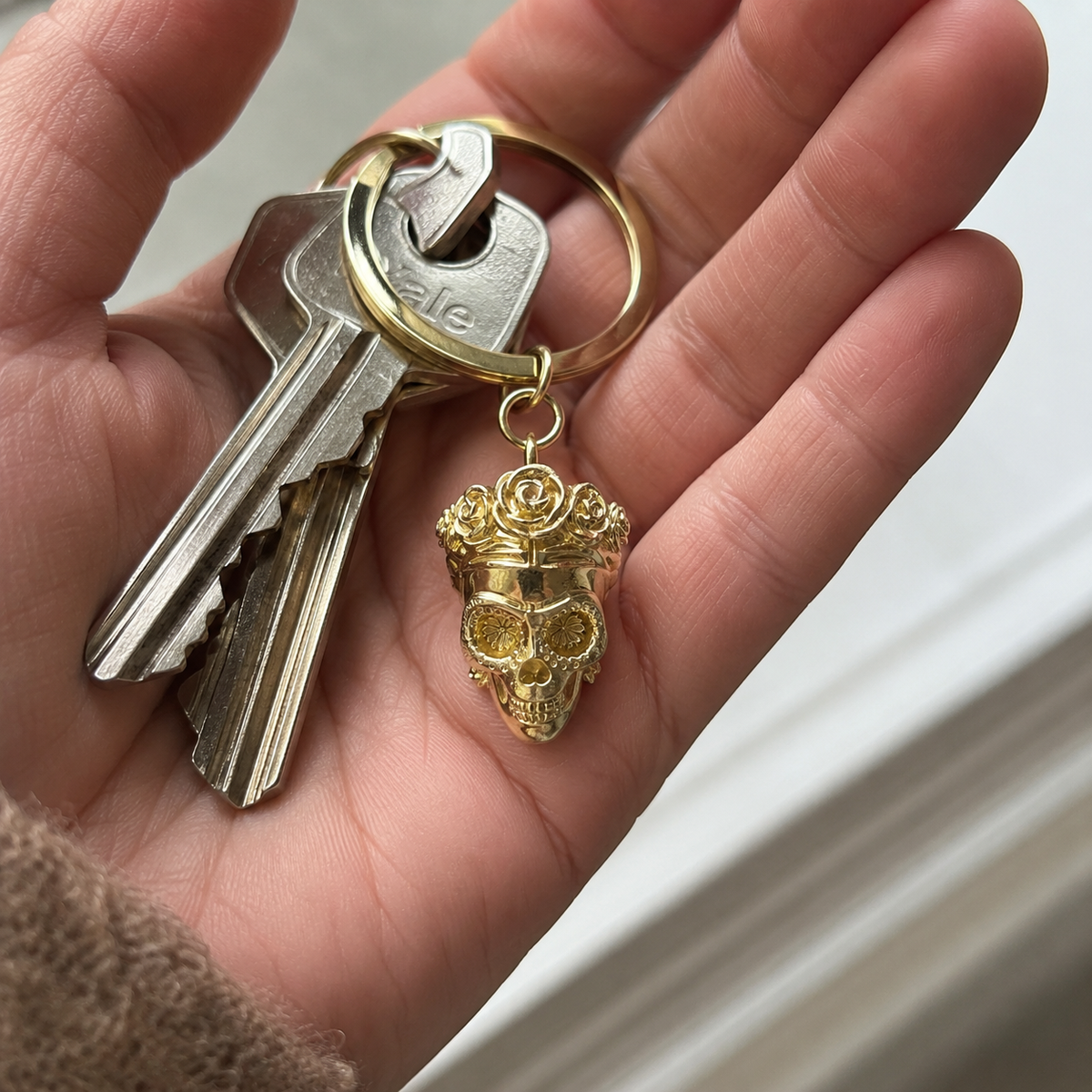 Frida Kahlo skull brass keyring attached to a set of keys in a natural lifestyle setting