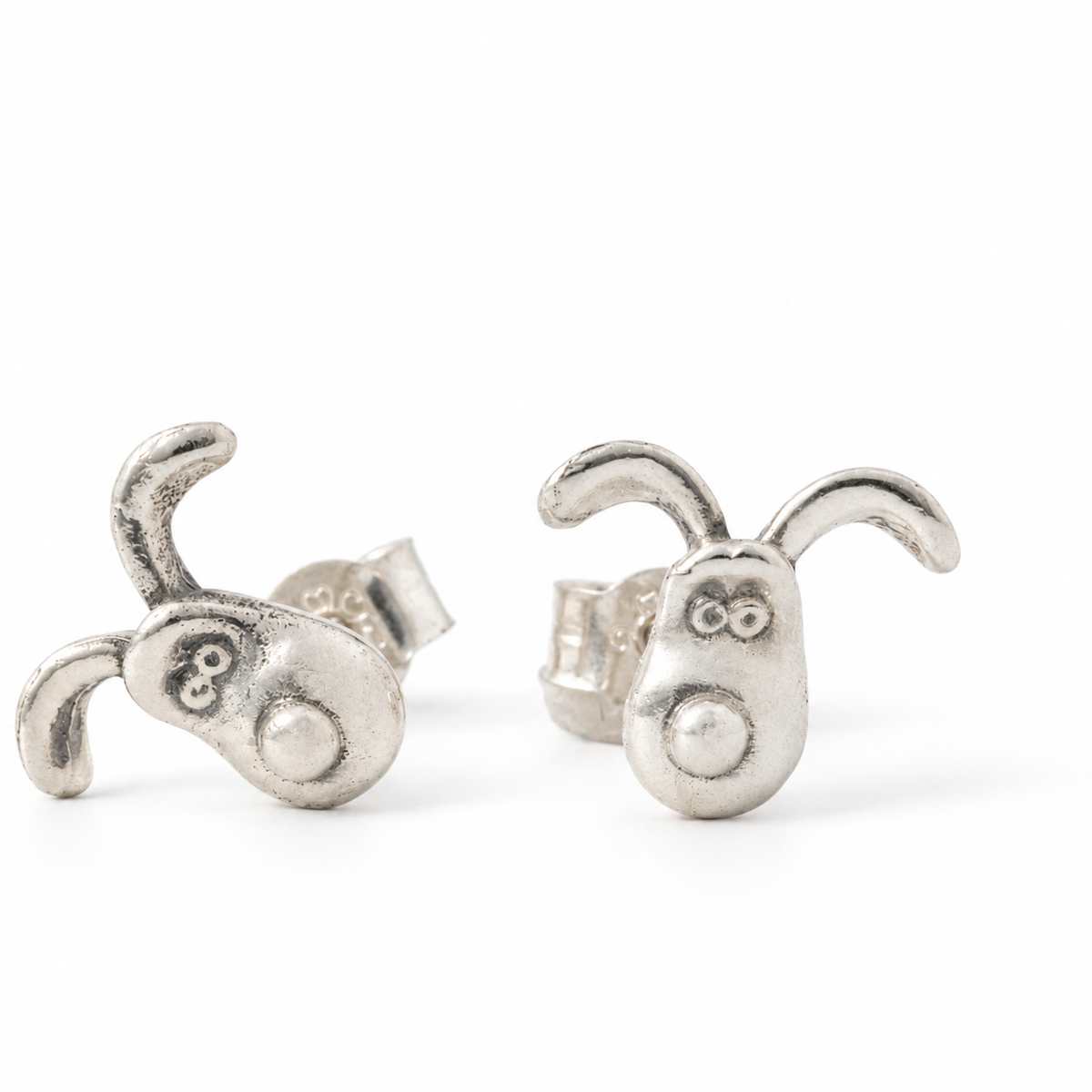 Close-up of sterling silver Gromit stud earrings showing their handmade texture and butterfly backs on a white background.