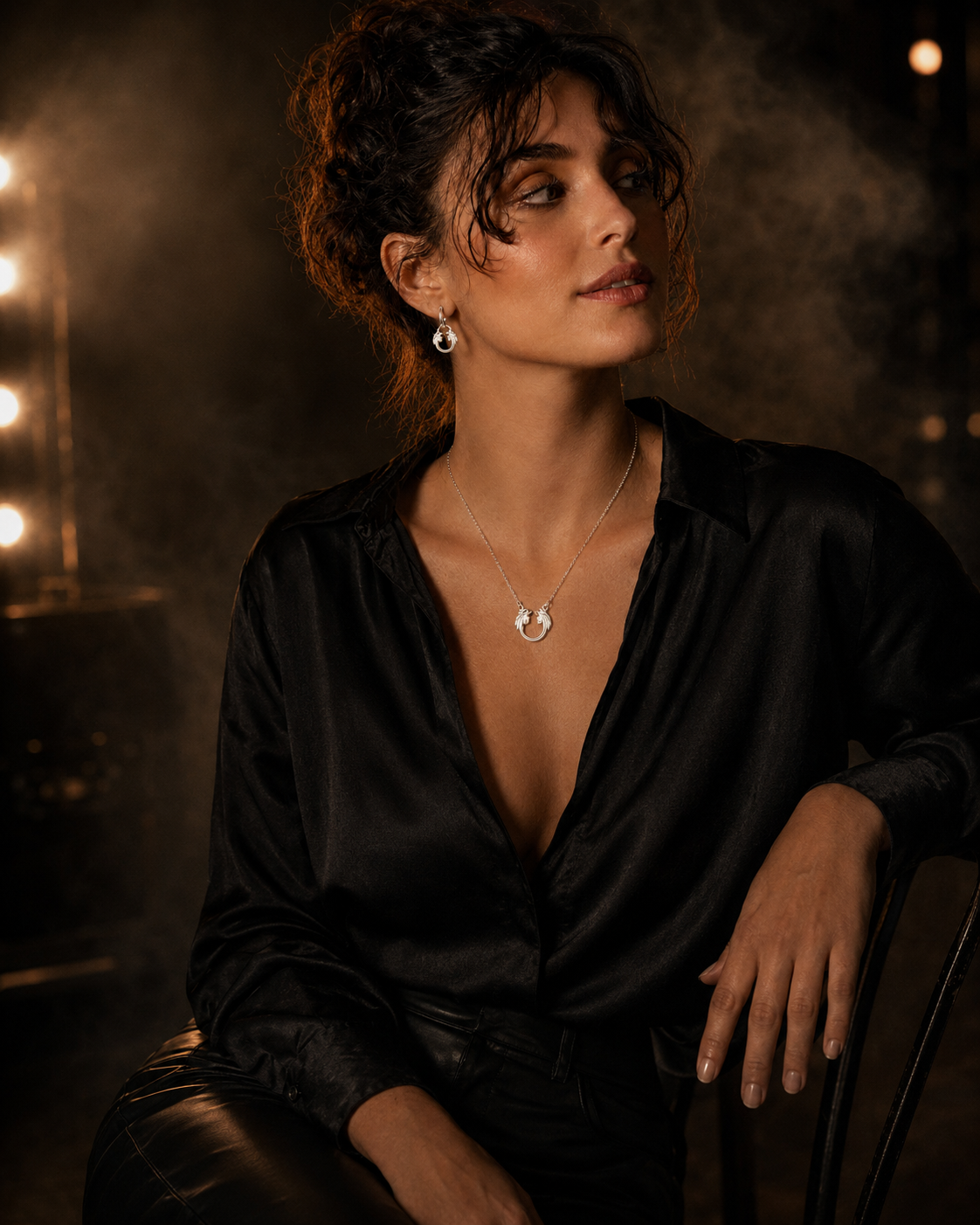 Woman in a black shirt sitting in a dimly lit room with lights in the background