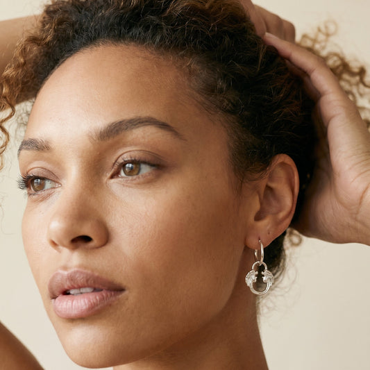 Model wearing Jesus Christ Superstar silver plated hoop earrings, official Andrew Lloyd Webber theatre jewellery for musical fans.