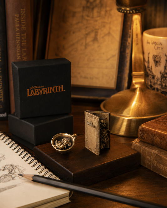 Labyrinth Character Book and Worm in a Cup bronze miniatures displayed with their collectible presentation boxes.