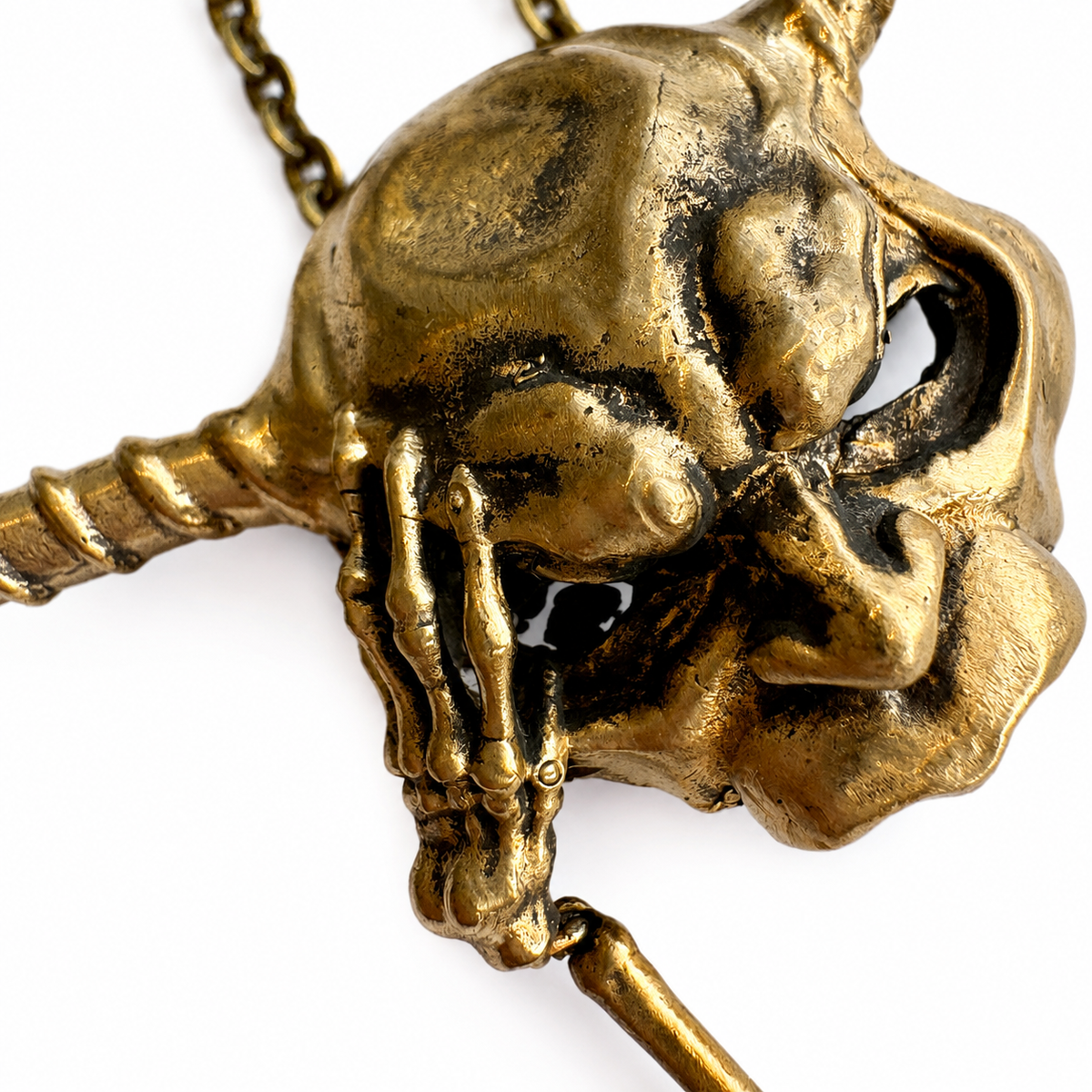 Close-up of the Goblin King mask necklace showing its sweeping horns, skeletal hand and antiqued bronze detail.