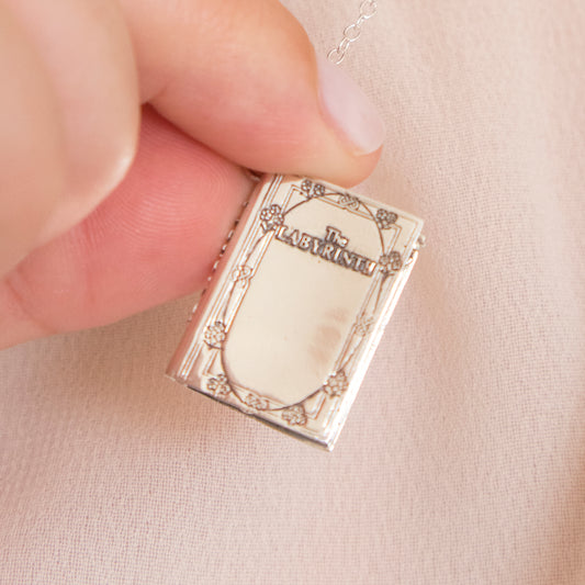 Close-up of the Labyrinth Story Book sterling silver necklace held in hand