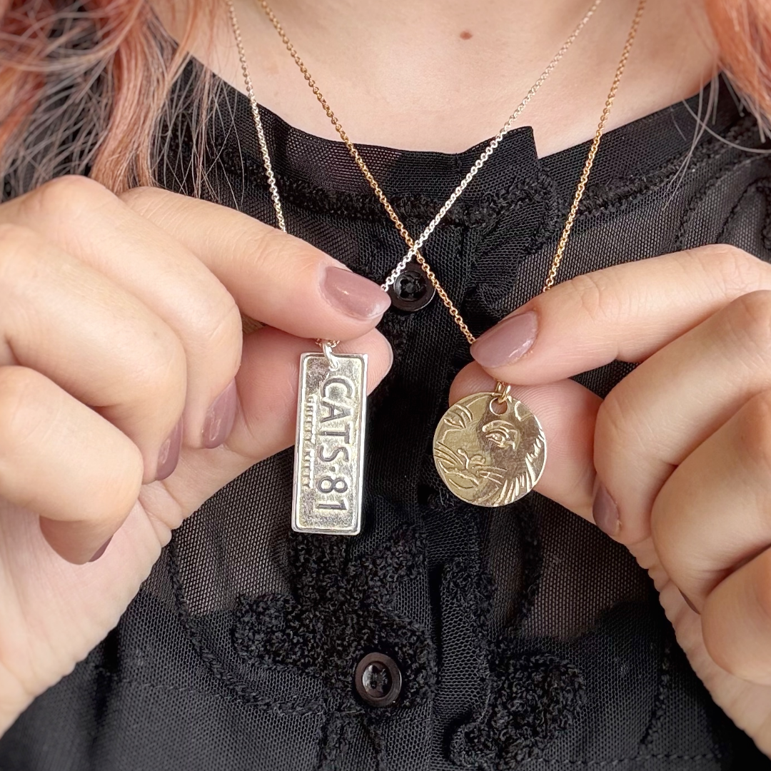 Official CATS jewellery showing CATS 81 silver necklace and Rum Tum Tugger gold necklace by Licensed To Charm